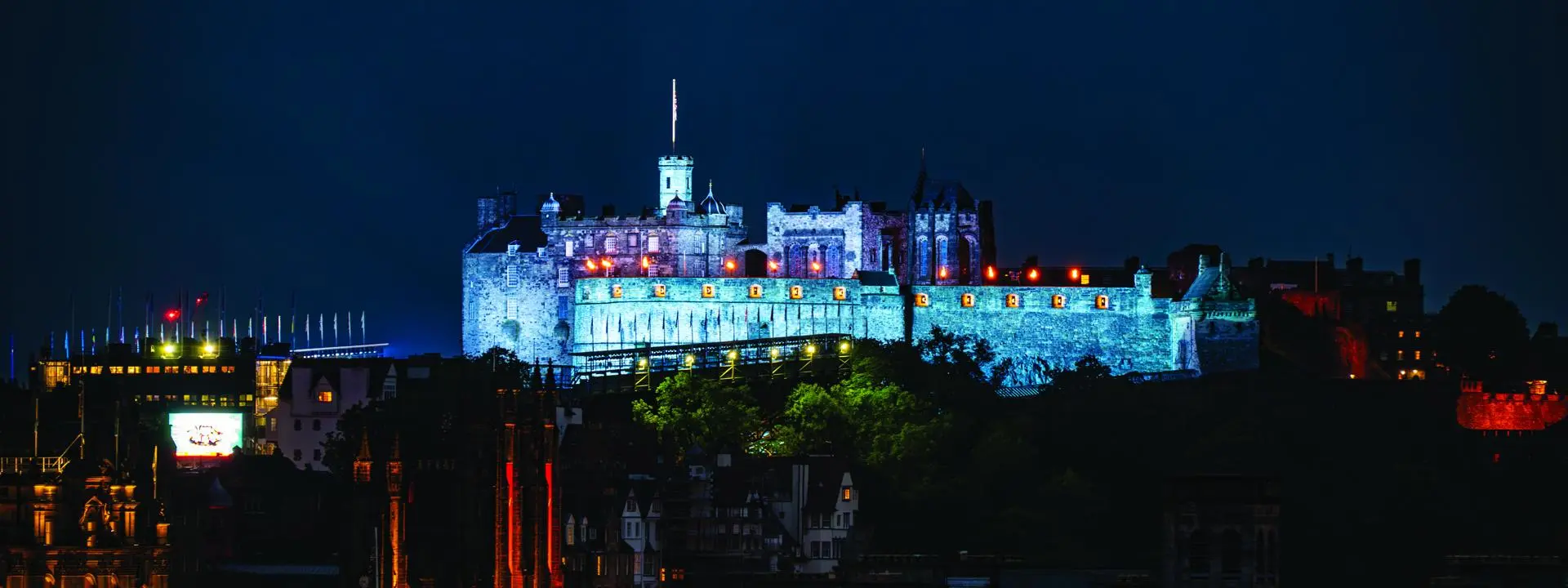 Long distance photo of Edinburgh Castle lit up at nightime.
