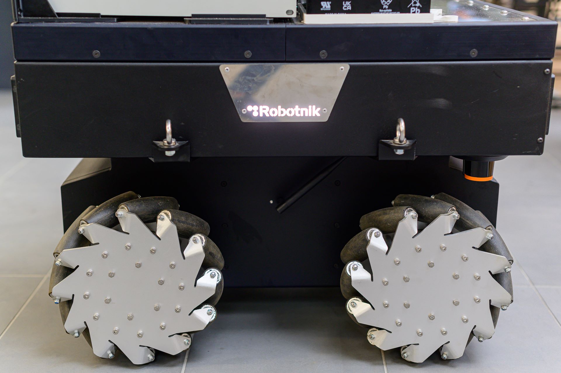This image shows a close-up view of a Robotnik-brand robotic platform with mecanum wheels.