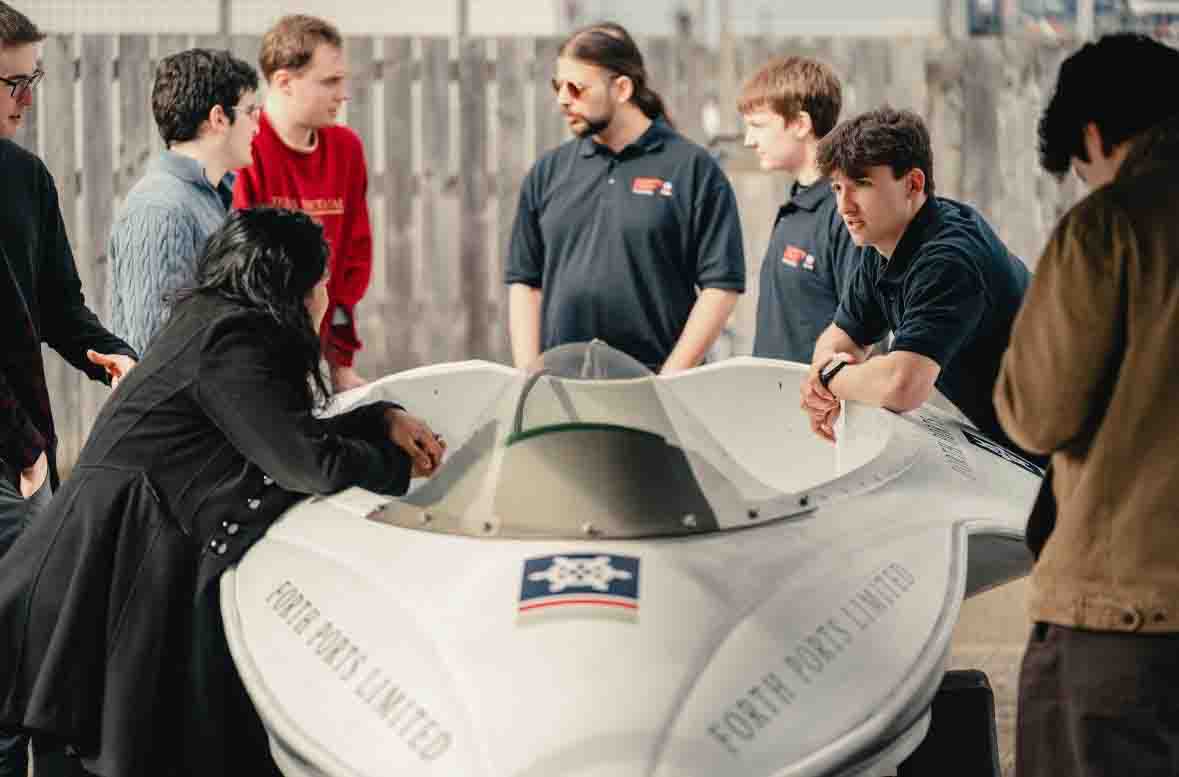 Images shows a member of the student team leaning on the boat.