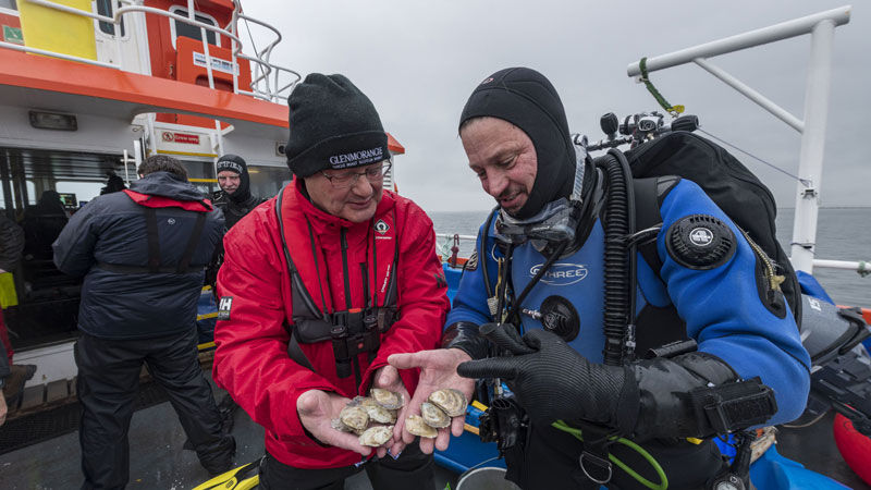 Glenmorangie’s Hamish Torrie and Dr Bill Sanderson. Picture courtesy of Glenmorangie Hamish Torrie and Dr Bill Sanderson, on a boat, holding oysters