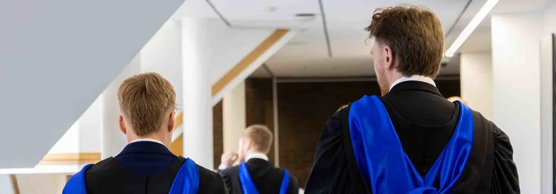 Two students walking in graduation gowns.