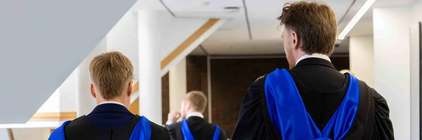Two graduates walking in a corridor