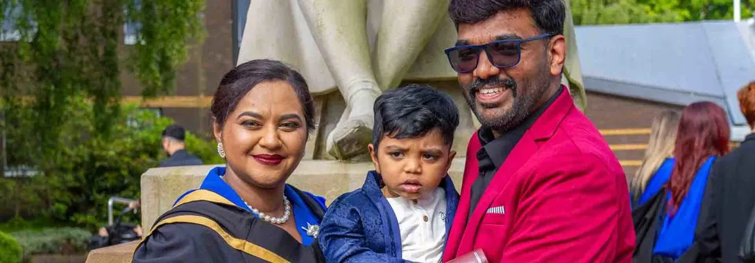 Helan Vinod with her son and husband, Linto Antony. Helan Vinod stands next to her husband and son outside the main entrance of Heriot-Watt University.
