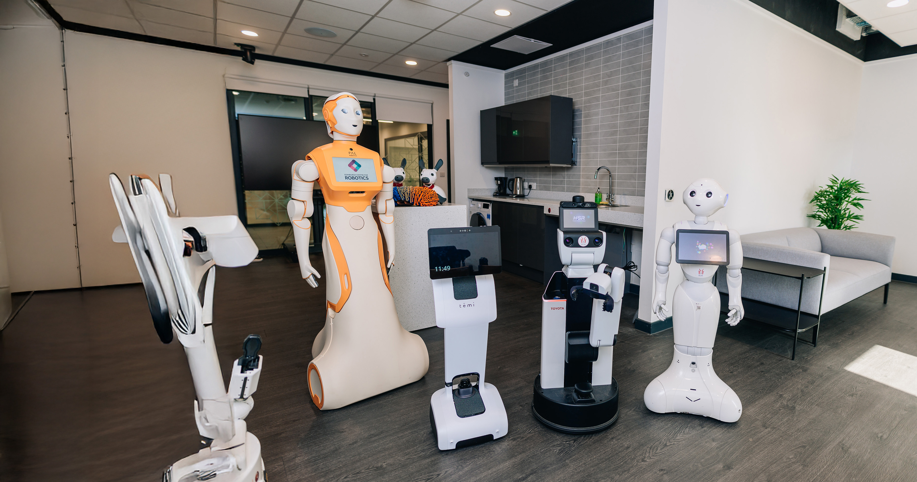 Robots of variuos heights and features, two with human-like faces, inside a home