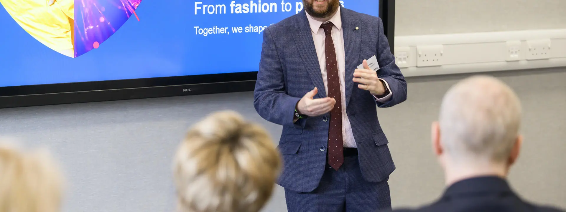 A person presenting on front of a screen that says 'From Fashion to Photons'.