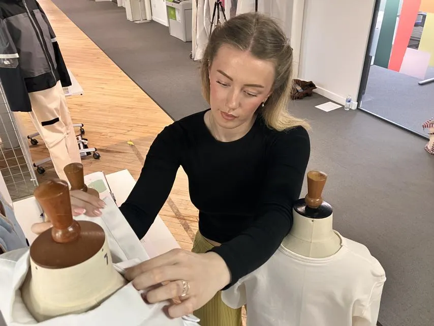 Farah Conn adjusting the fit of one of the garments.