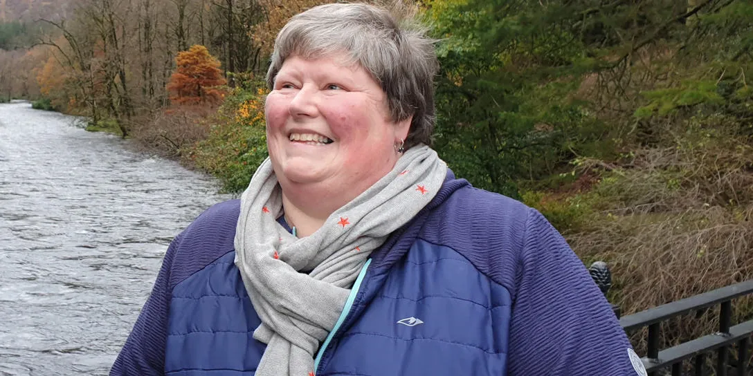 Rev. Jane Howitt, Heriot Watt University Chaplain, with path and shrubs behind her
