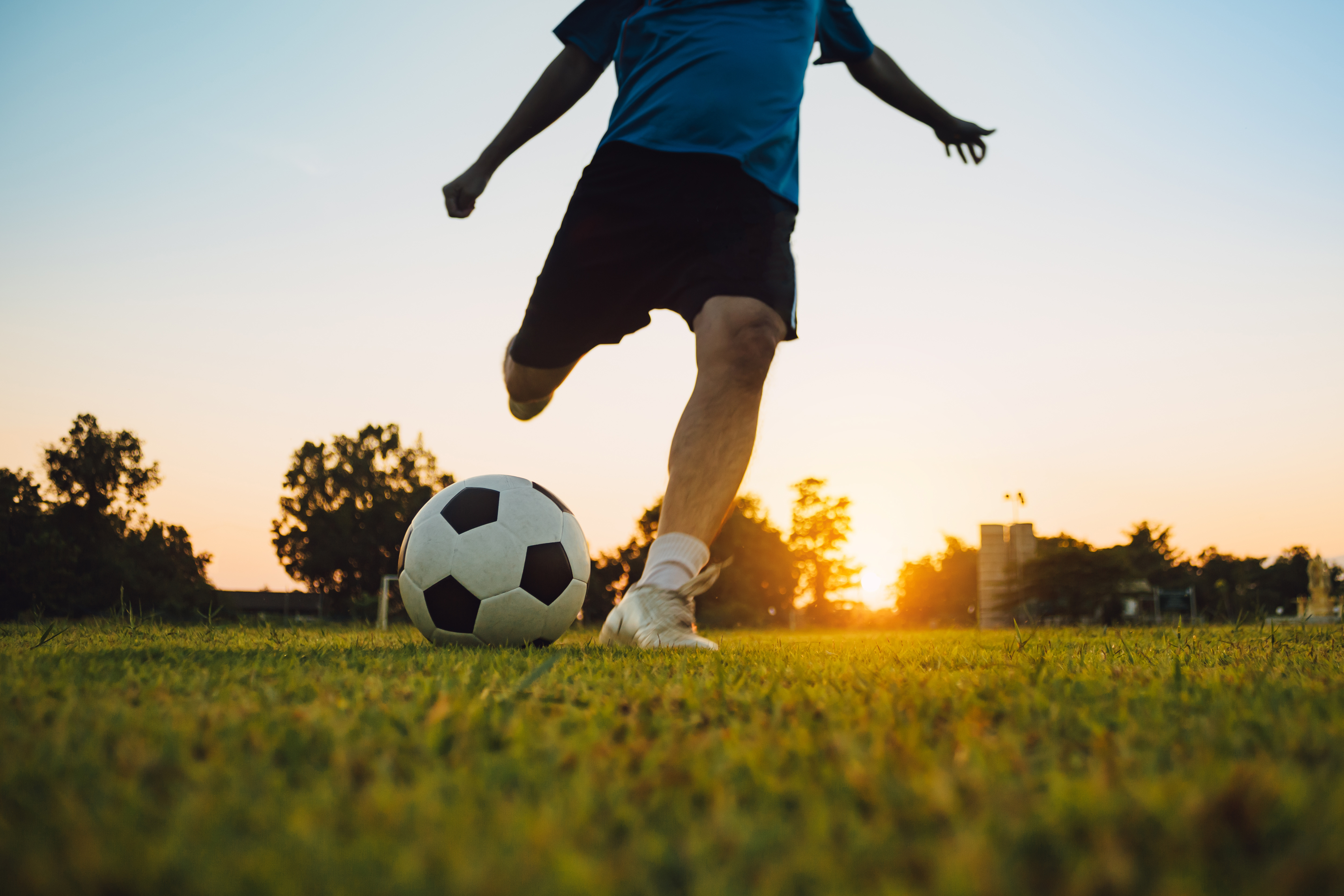 Silhouette action sport outdoors of a group of kids having fun playing soccer football 
