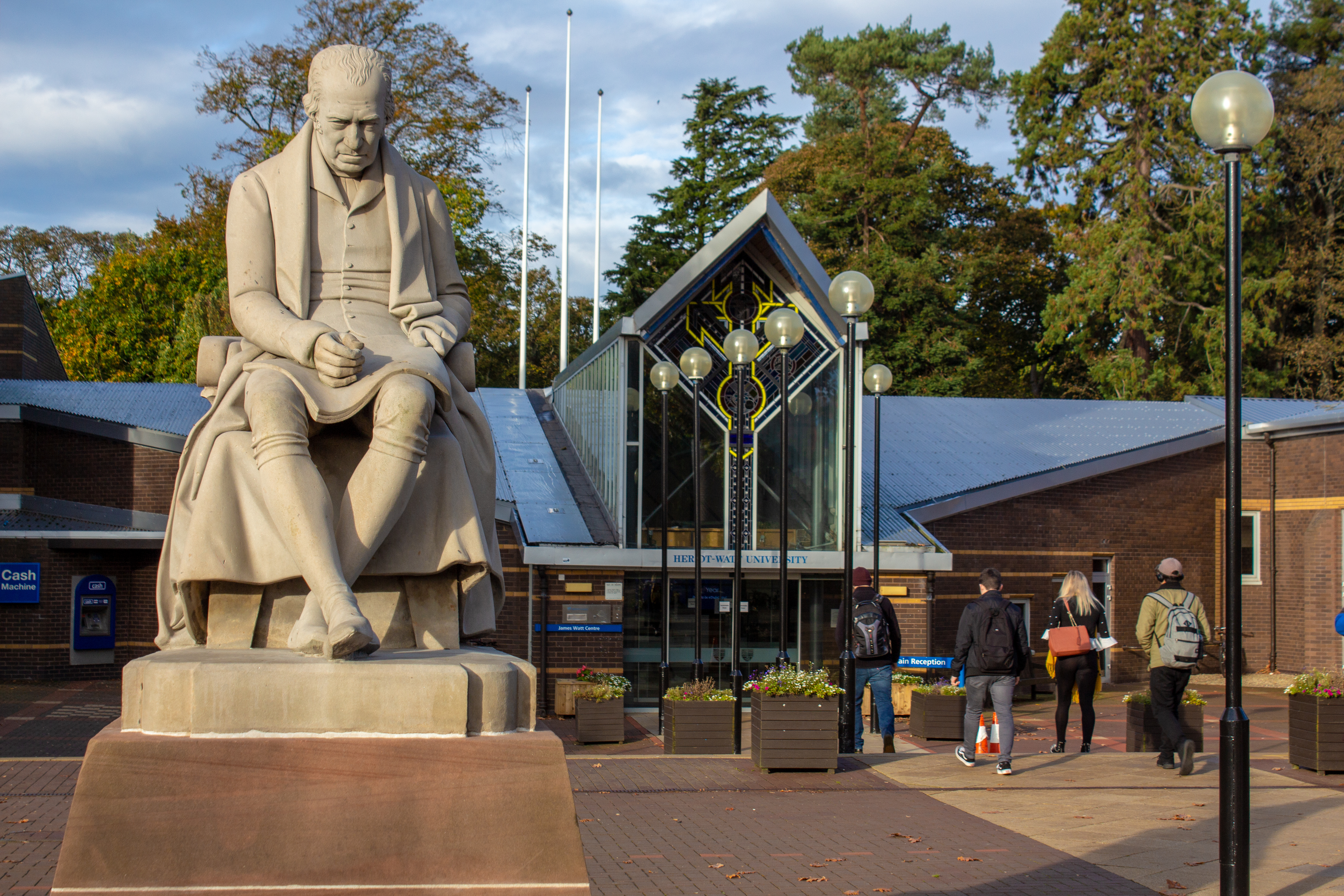 Statue of James Watt in foreground, main entrance to university buildings behind.