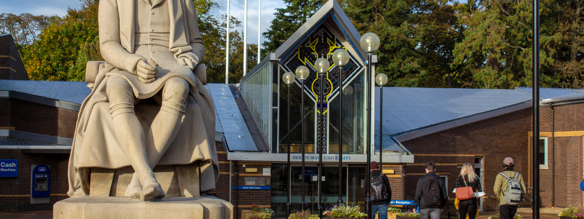 Statue of James Watt in foreground, main entrance to university buildings behind.