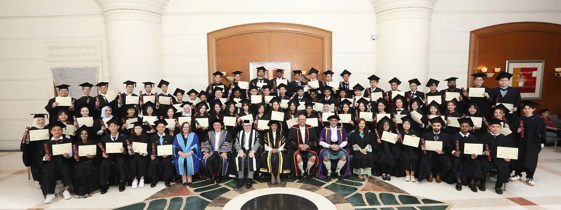 A group of graduates smiling and posing for a photo inside a building, celebrating their academic achievements together.