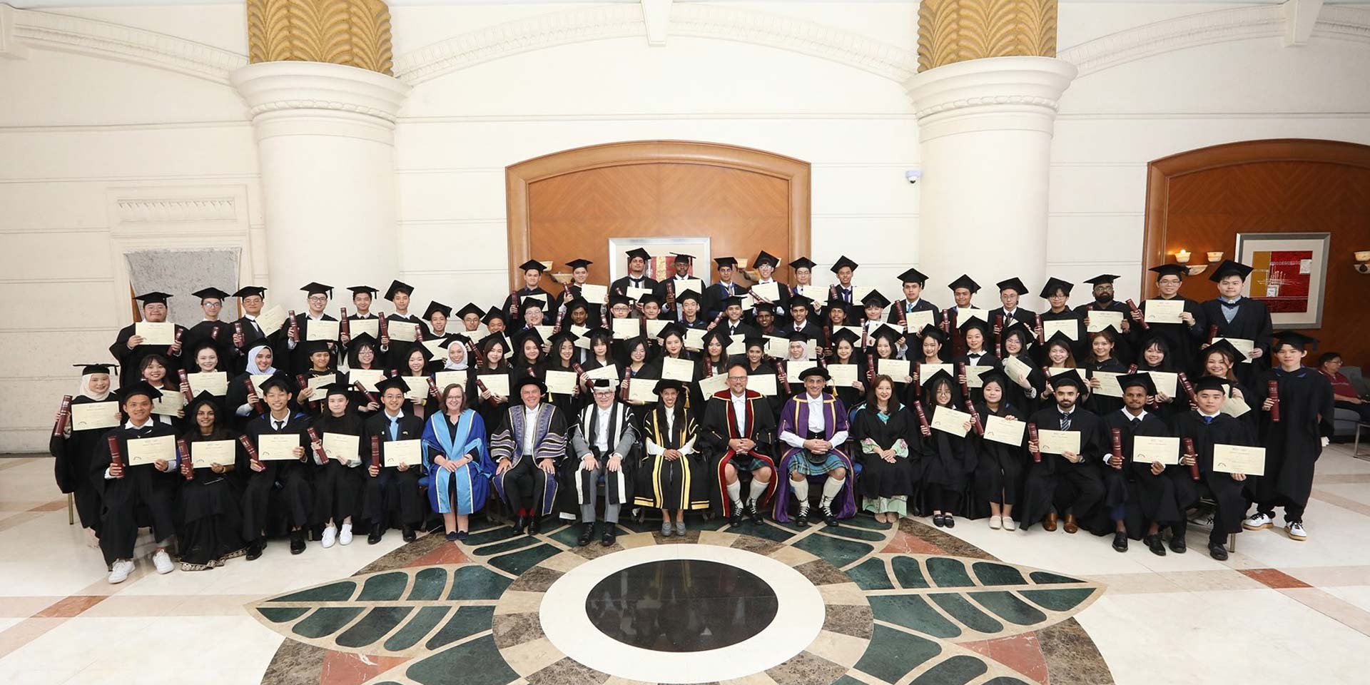 A group of graduates smiling and posing for a photo inside a building, celebrating their academic achievements together.