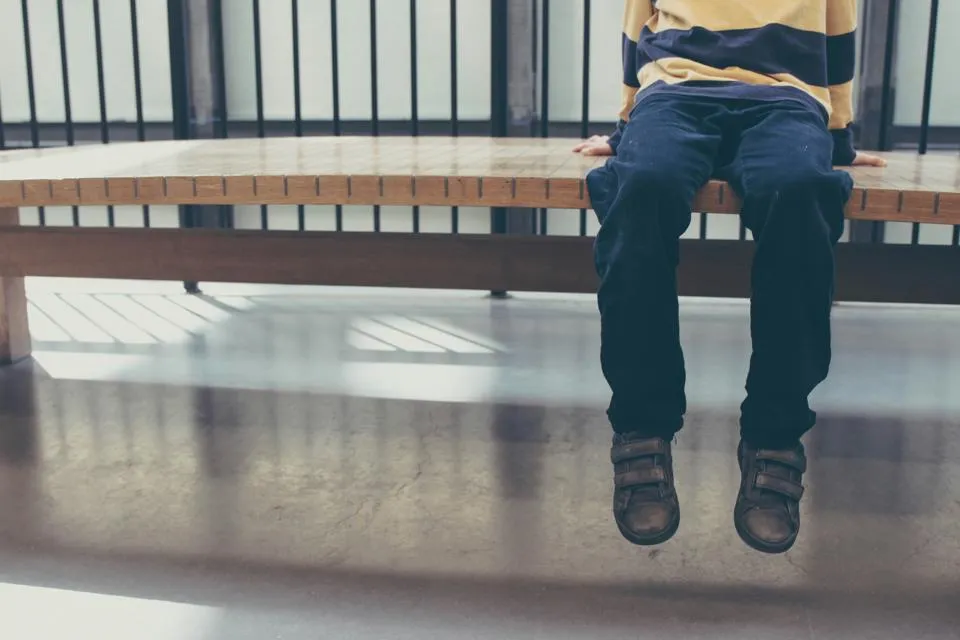 Boys legs sitting on a bench.