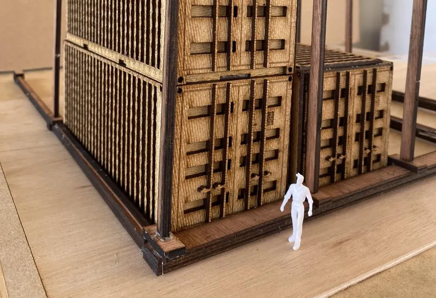 Part of the shipping container model Habiba created from fibreboard. A shipping container model next to a scale model of a man.