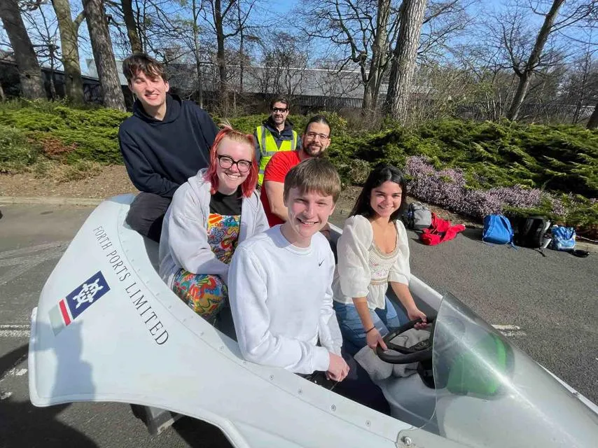 Student team members sitting in the Experiment of Leith H2 , (back row): Dominic Chapman L - R (middle row): Kate Sinclair and Andrei Muntean L - R (front row): Logan Taylor and Emilin Isgin. Image of the five students sitting in their boat.