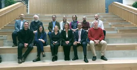 A group of people in business attire are sat across a large stairway at The National Robotarium