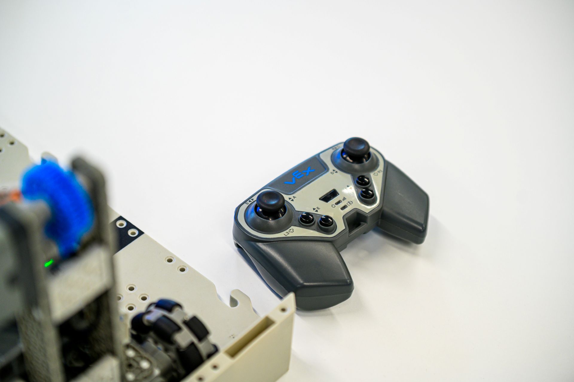 A handheld VEX robotics controller rests on a white tabletop
