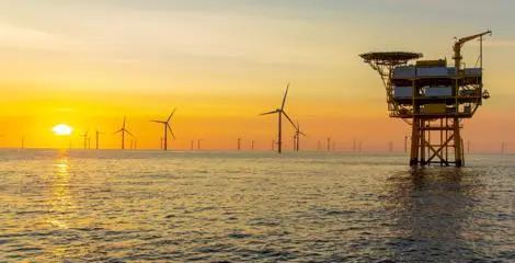 Oil and gas station in open sea with wind farm in background
