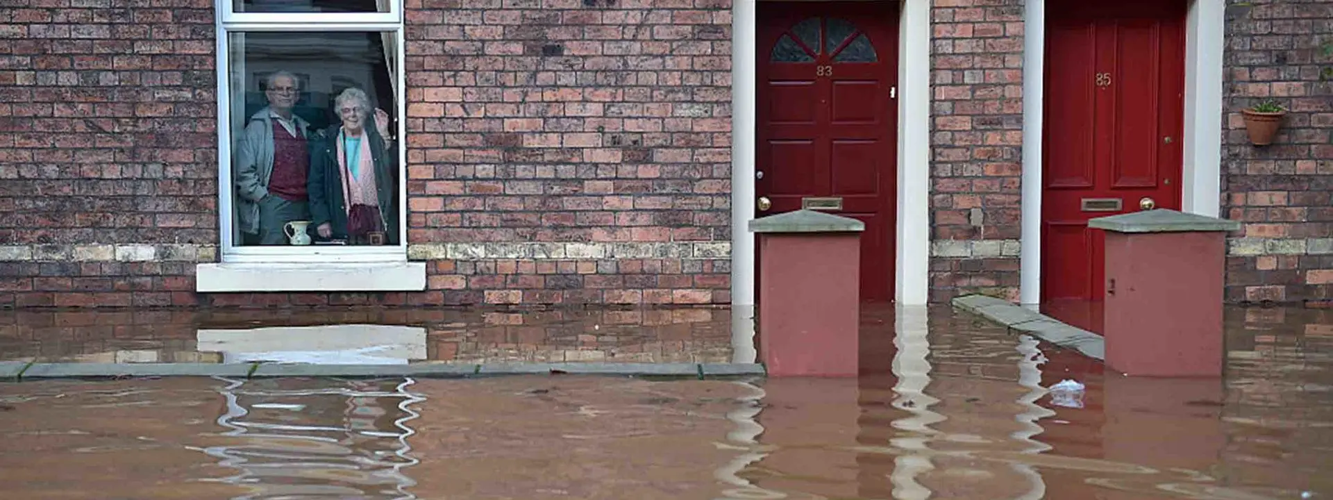 Image shows two older people trapped in their homes by flood waters.