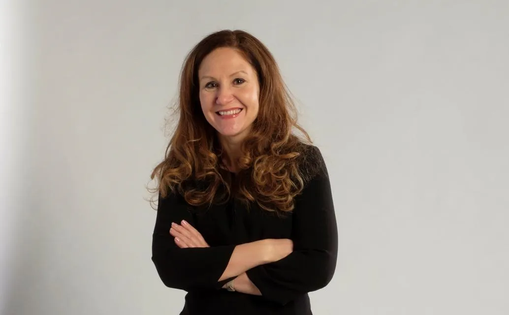 A woman with long, wavy hair wearing a black outfit
