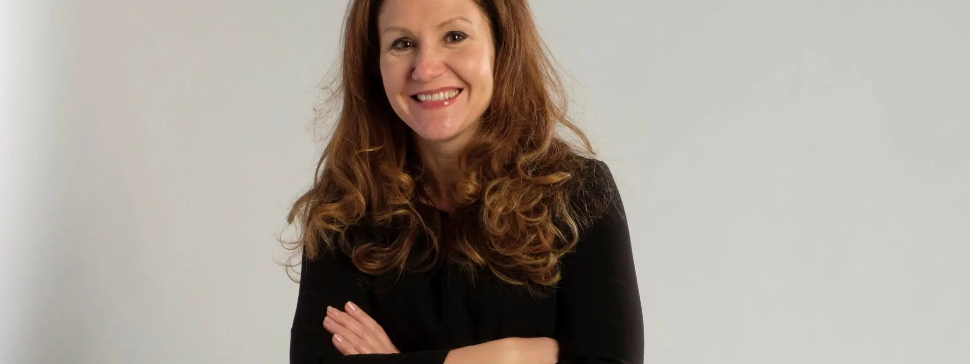 A woman with long, wavy hair wearing a black outfit