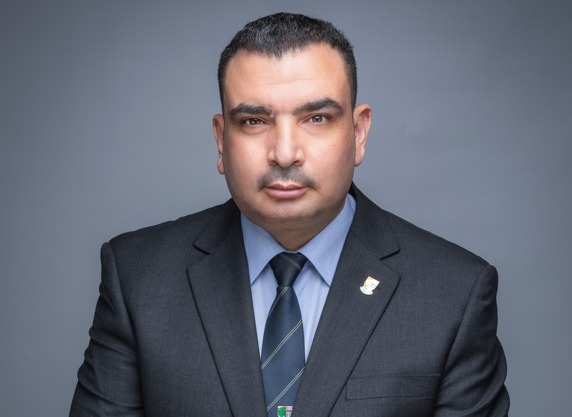 Professor Rabee Rustum in a grey suit with a light blue shirt and dark blue tie. 