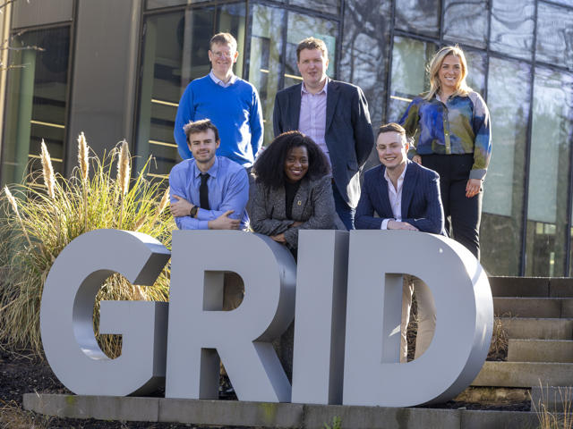 Heriot-Watt and CGI stakeholders stand behind the university's Heriot-Watt's Global Research Innovation Discovery sign