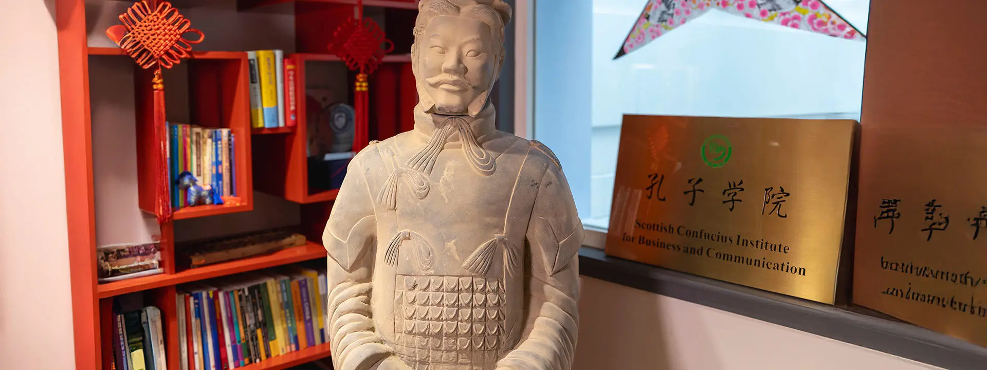Terracotta warrior statue head and shoulders in Confucius Institute with bookshelf behind
