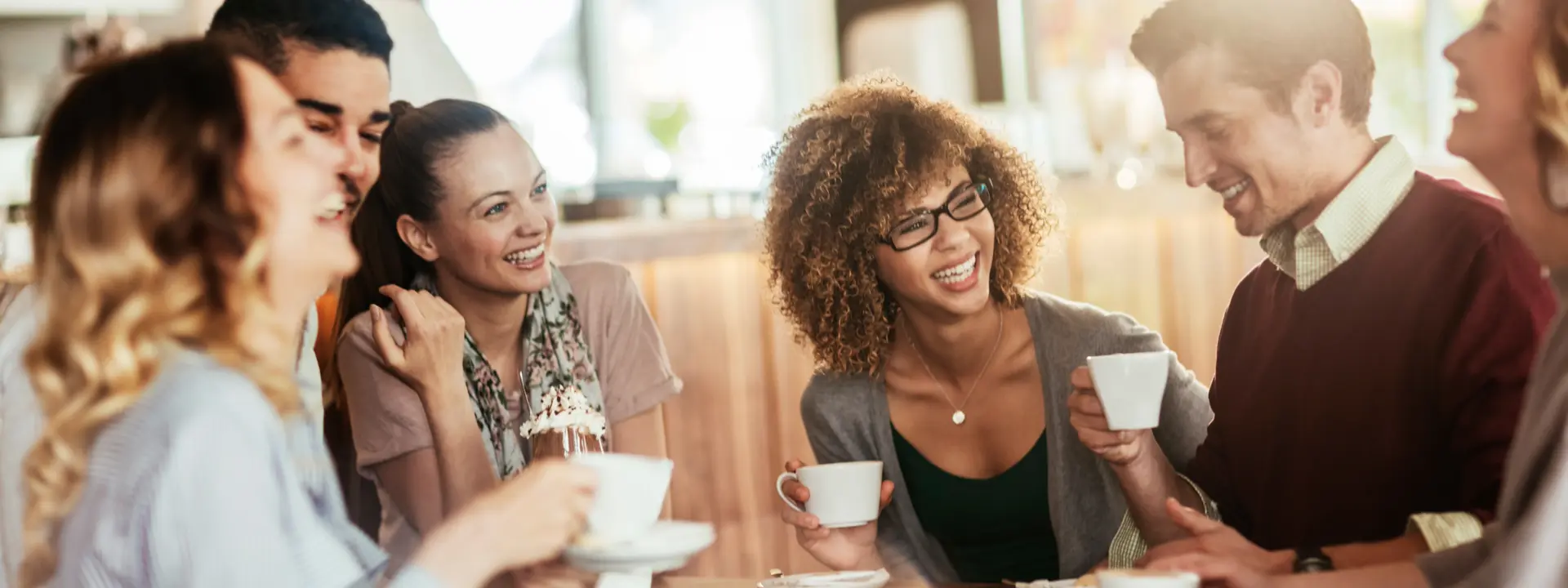 People sitting around a table talking and drinking coffee.