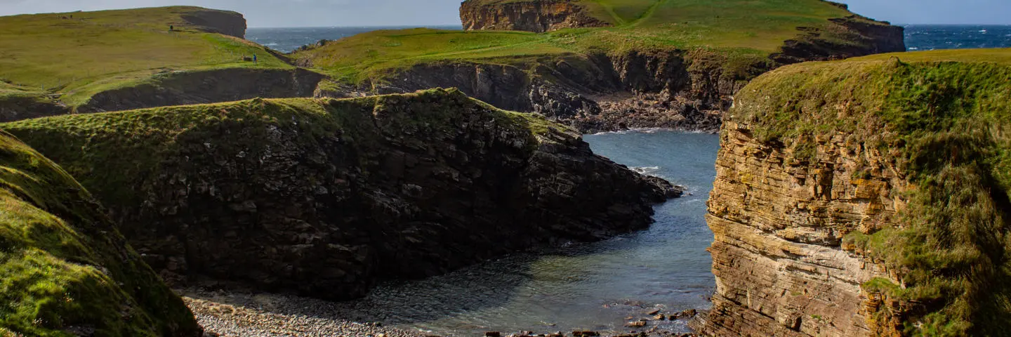 Coastline with green hills and rocky outcrops.