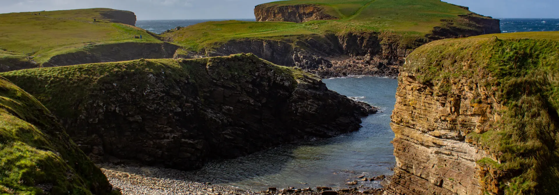 Coastline with green hills and rocky outcrops.
