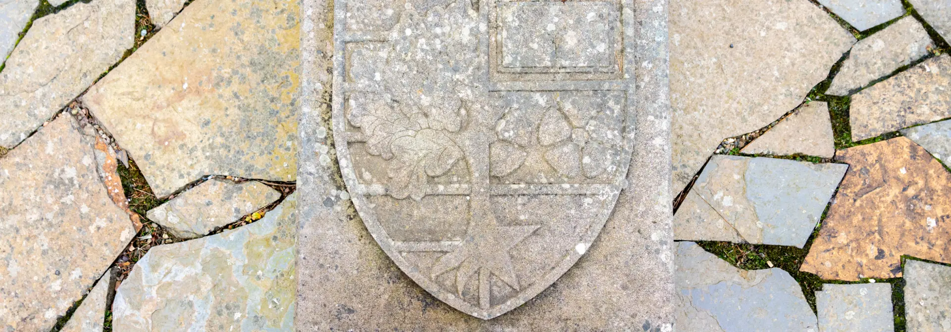 Close up picture of the millenium garden plaque inlaid on stone paving with the Heriot-Watt shield symbol.