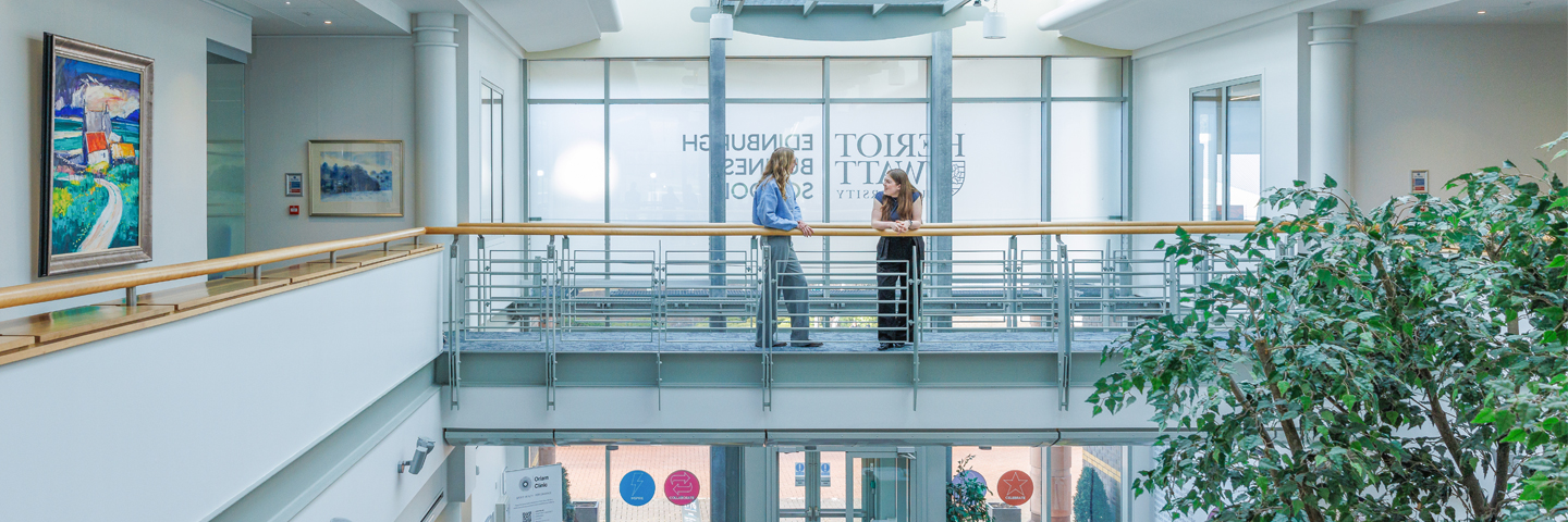 Two students talking on the upper-level walkway above EBS lobby.