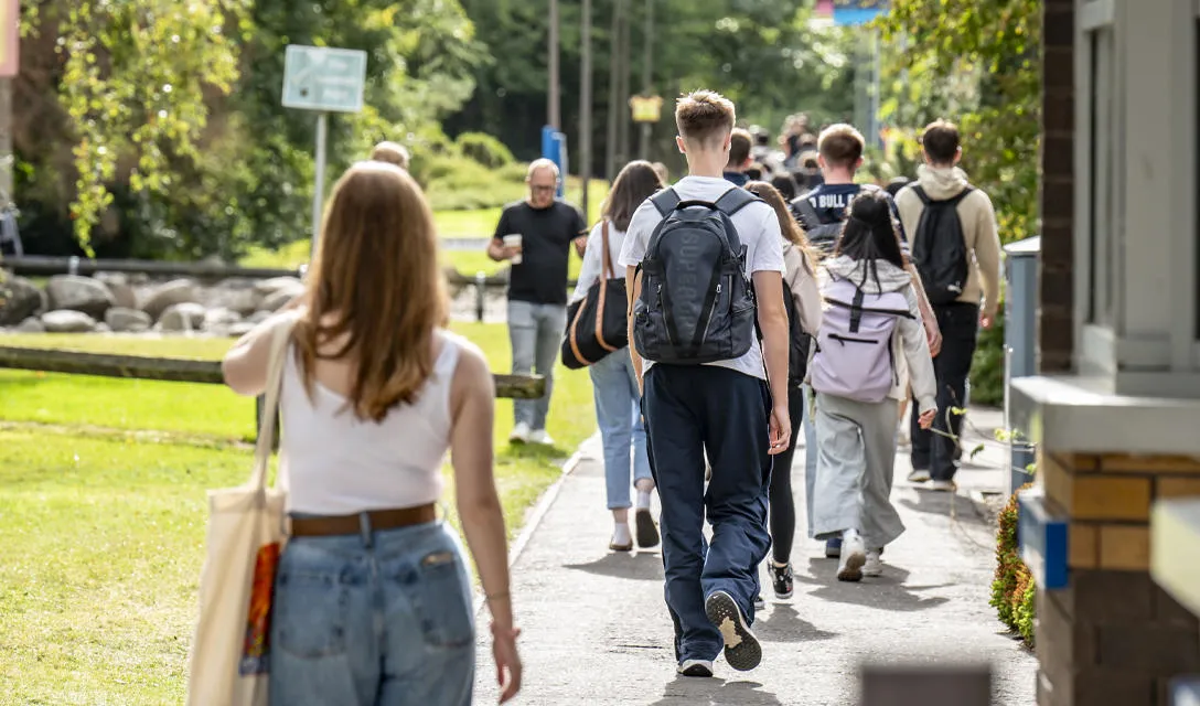 Students stroll down a sidewalk, chatting and laughing as they head to their next class or activity.