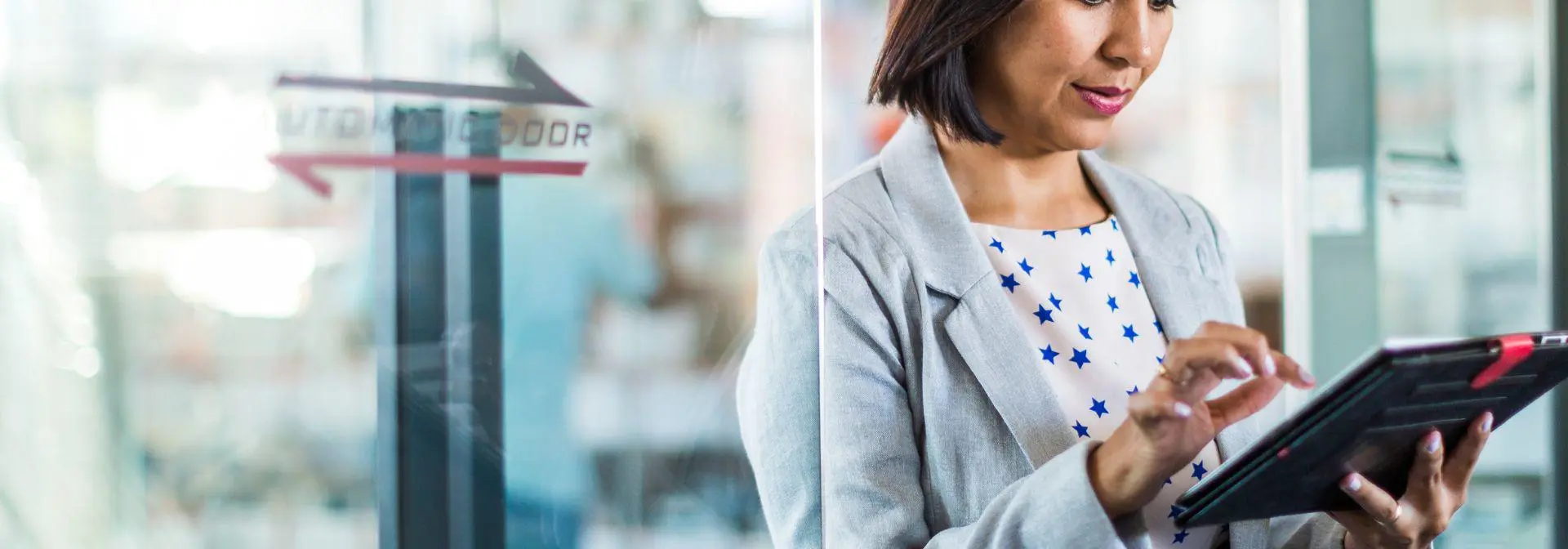 A woman stands studying information on a tablet device