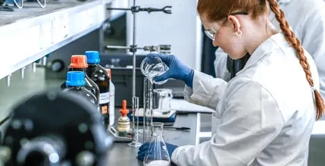 Chemistry student pouring liquid into a measuring flask