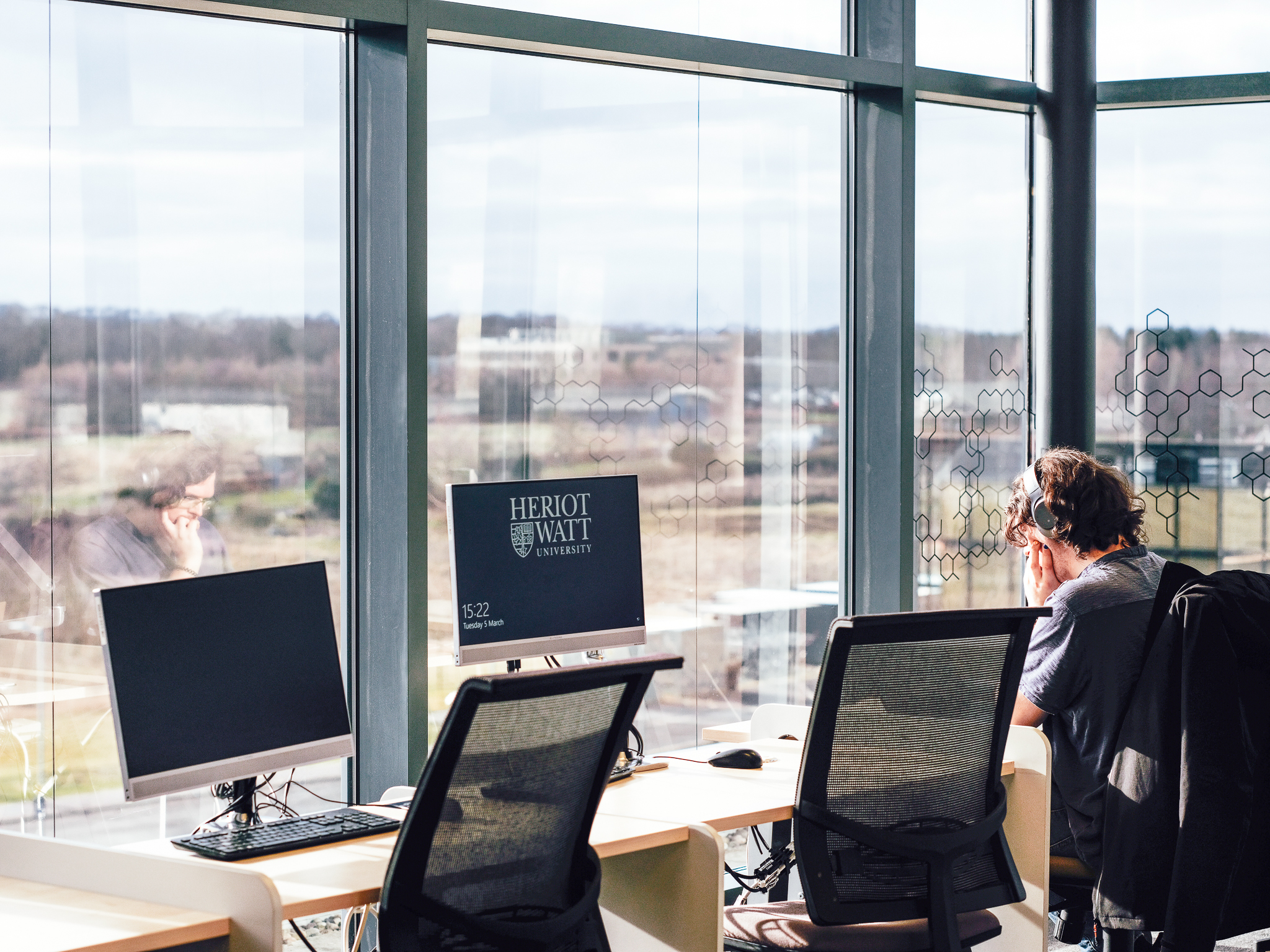A student working at a computer in a common area by the window