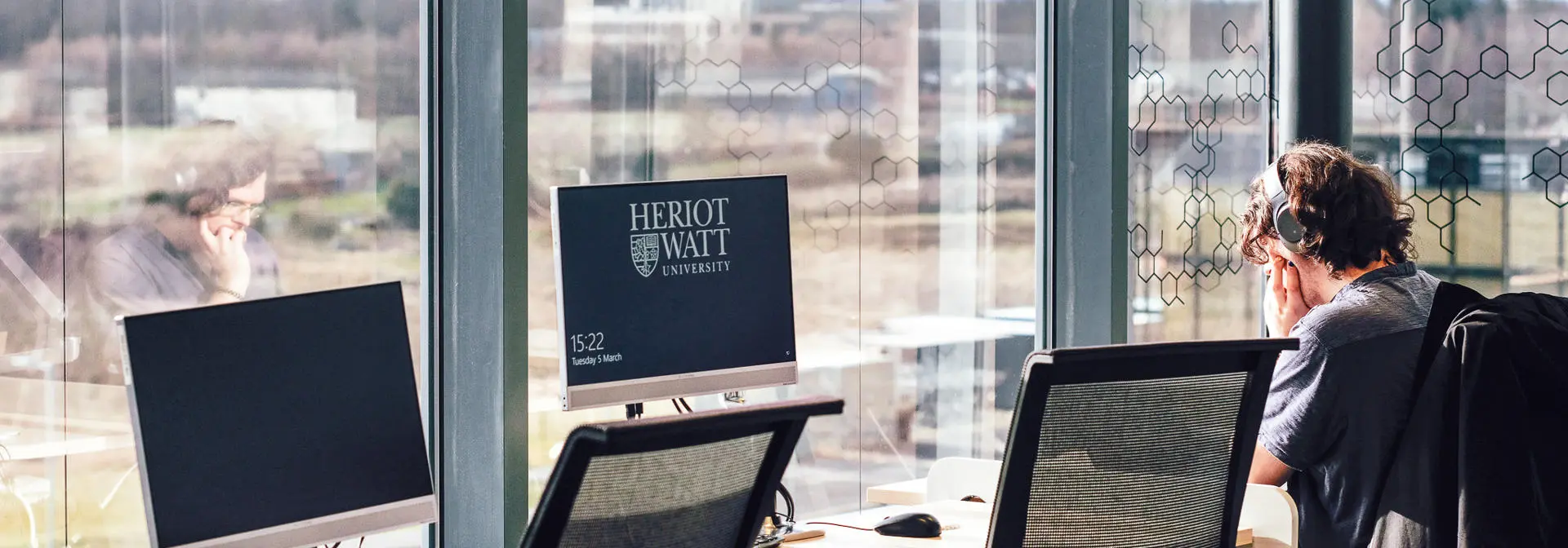 A student working at a computer in a common area by the window