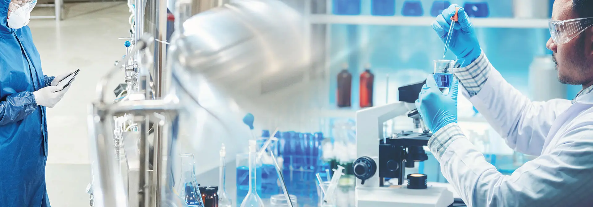 Two individuals in lab coats and gloves collaborate on a scientific project in a laboratory setting.