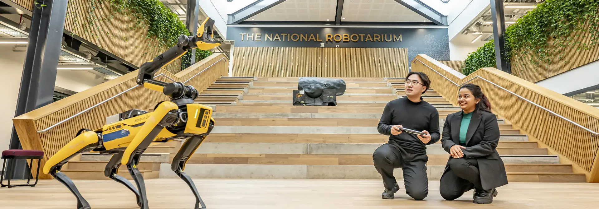 Students controlling a yellow robot dog at The National Robotarium