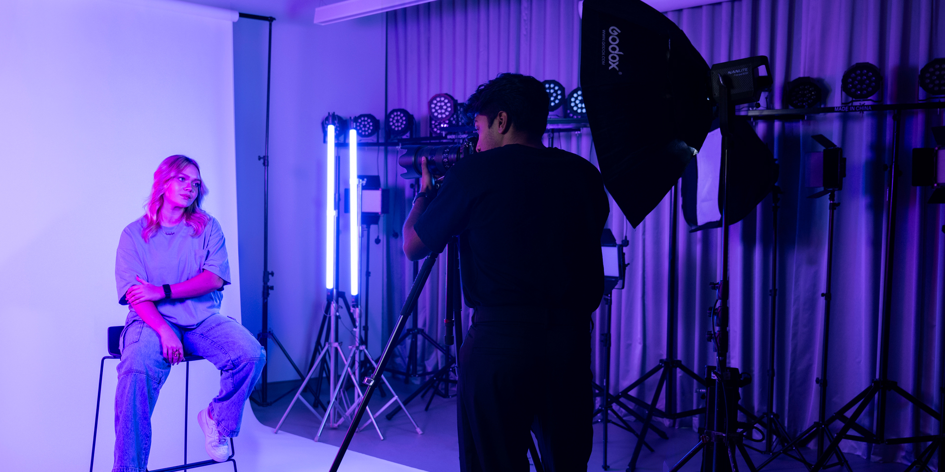 student photographer taking a portrait of model in photography lab