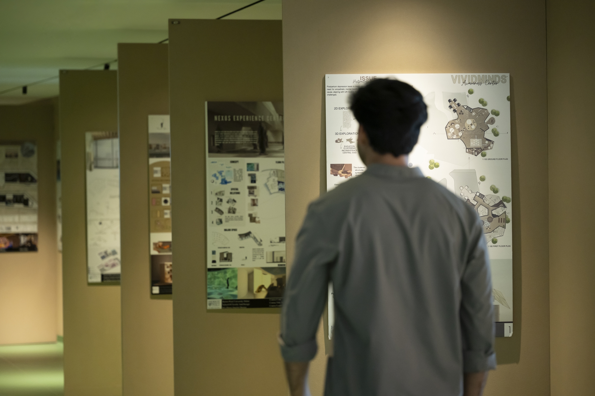 student walking past posters of architecture projects on the wall