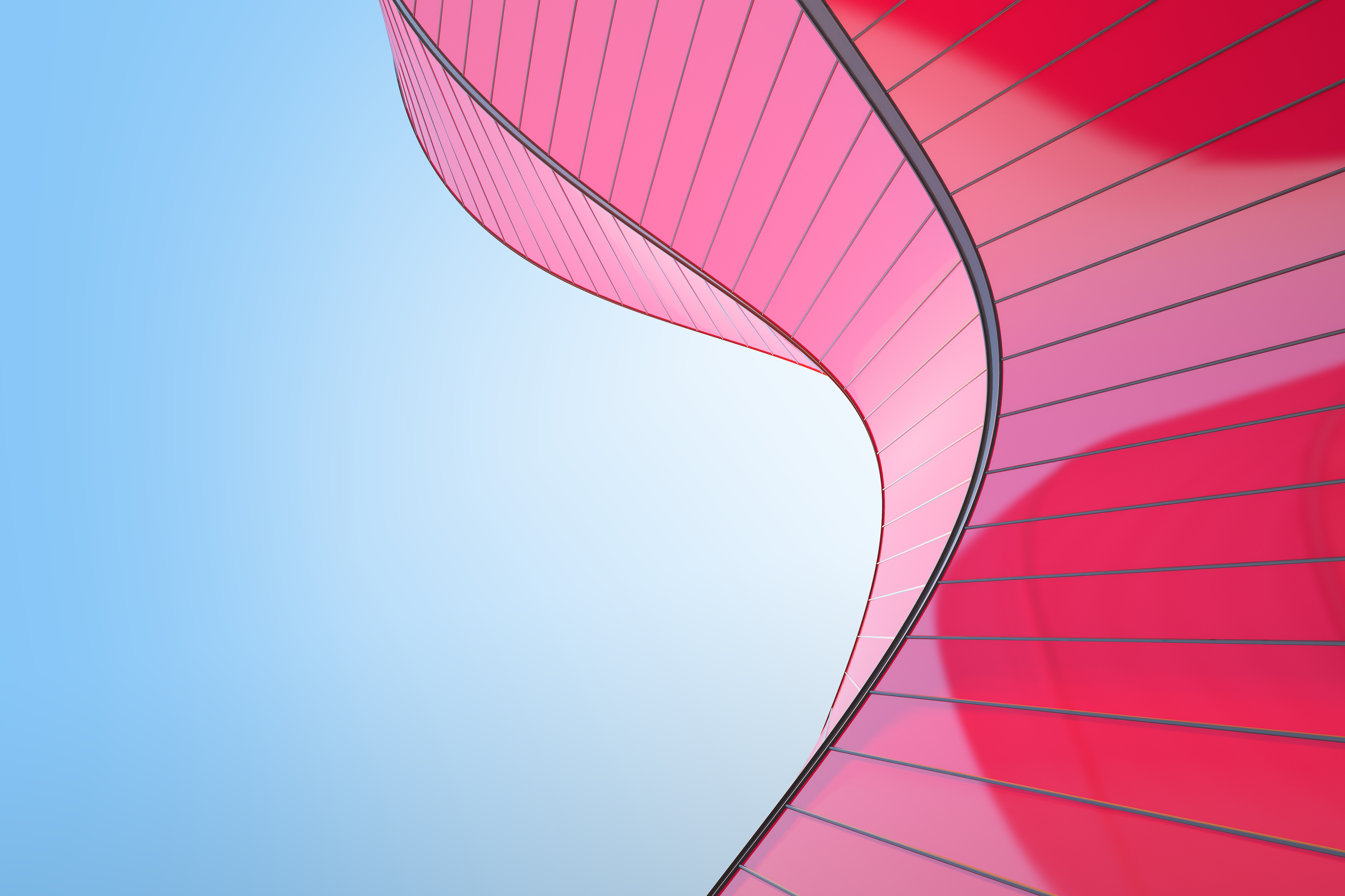 A red curved geometric building structure against a clear blue sky