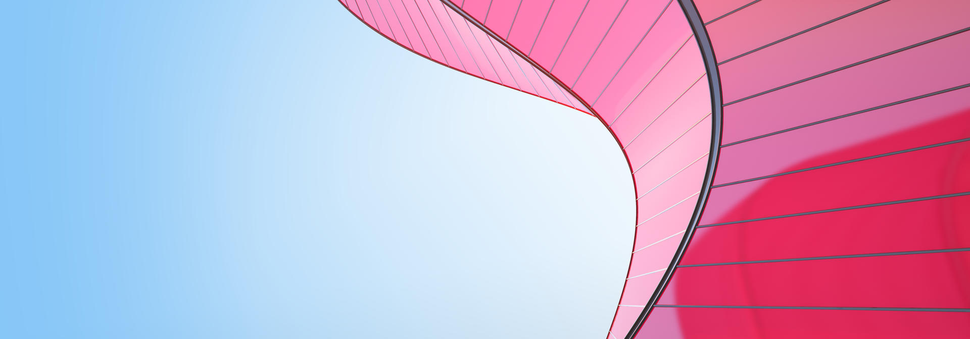 A red curved geometric building structure against a clear blue sky