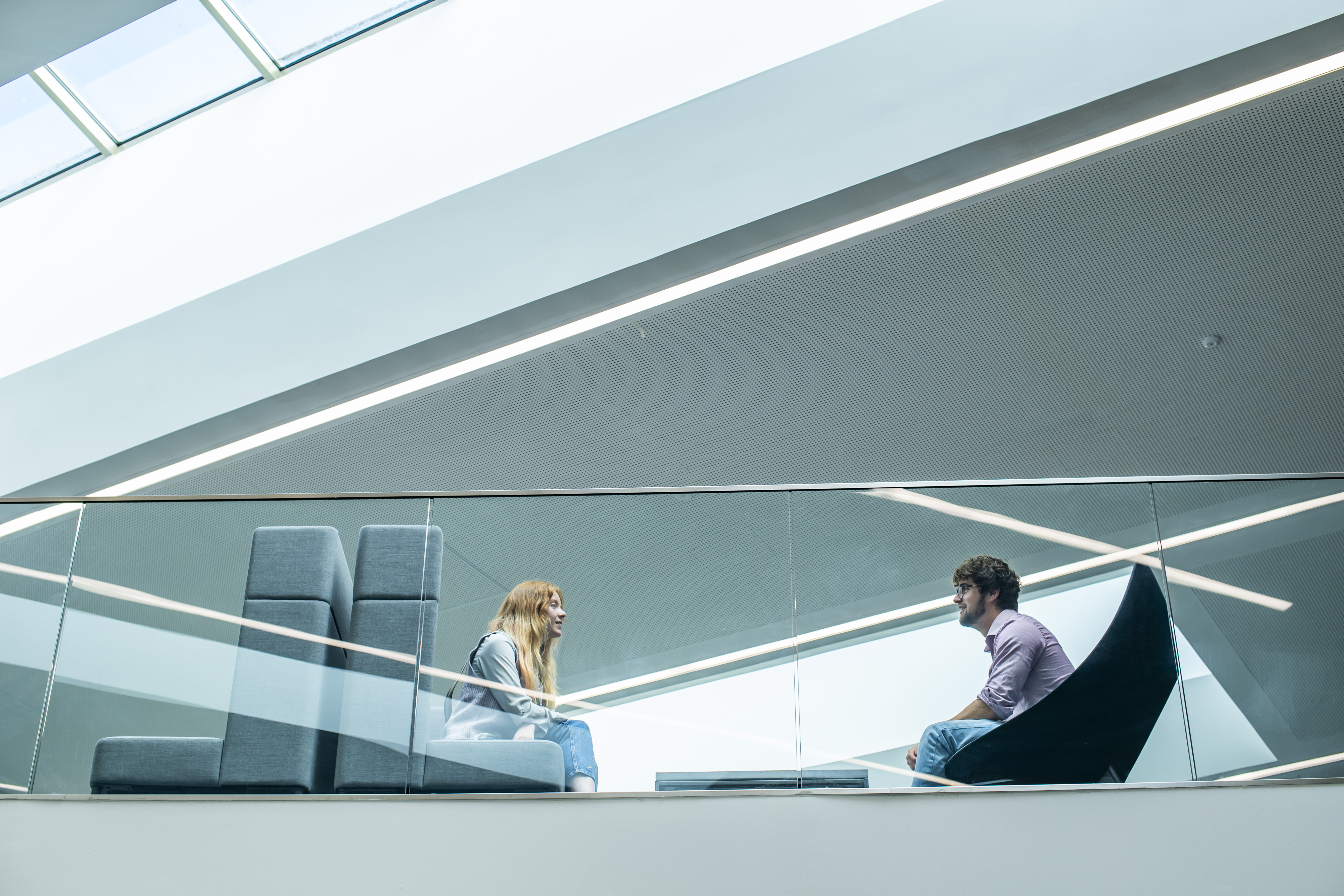 A female and male student speaking to each other in a modern bright space