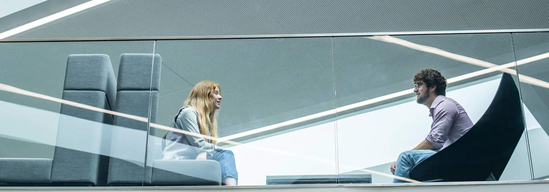 A female and male student speaking to each other in a modern bright space