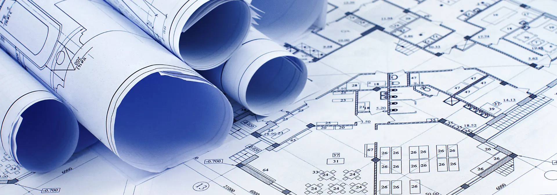 Blueprint building construction paperwork rolled up and laid out on a table