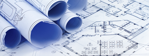 Blueprint building construction paperwork rolled up and laid out on a table