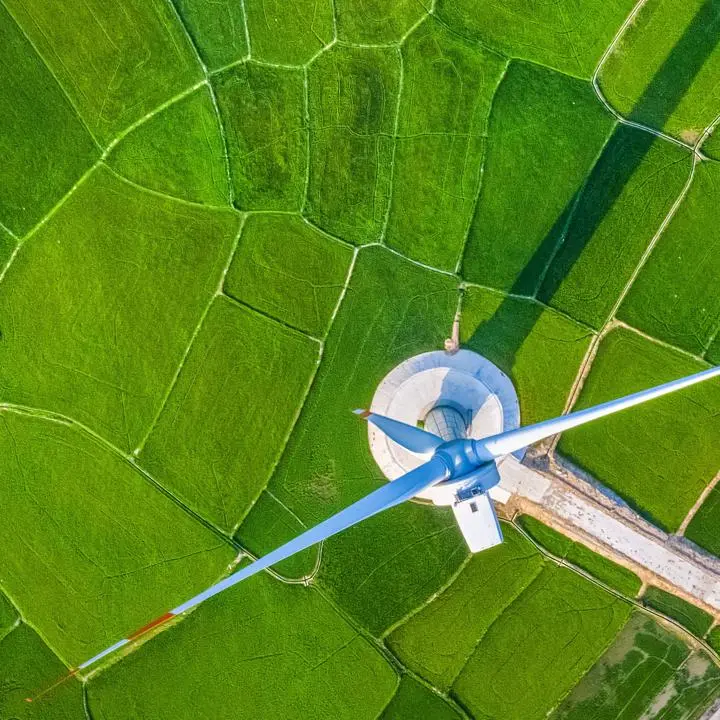 A green landscape with long walking paths to a single wind turbine from a bird's eye view.