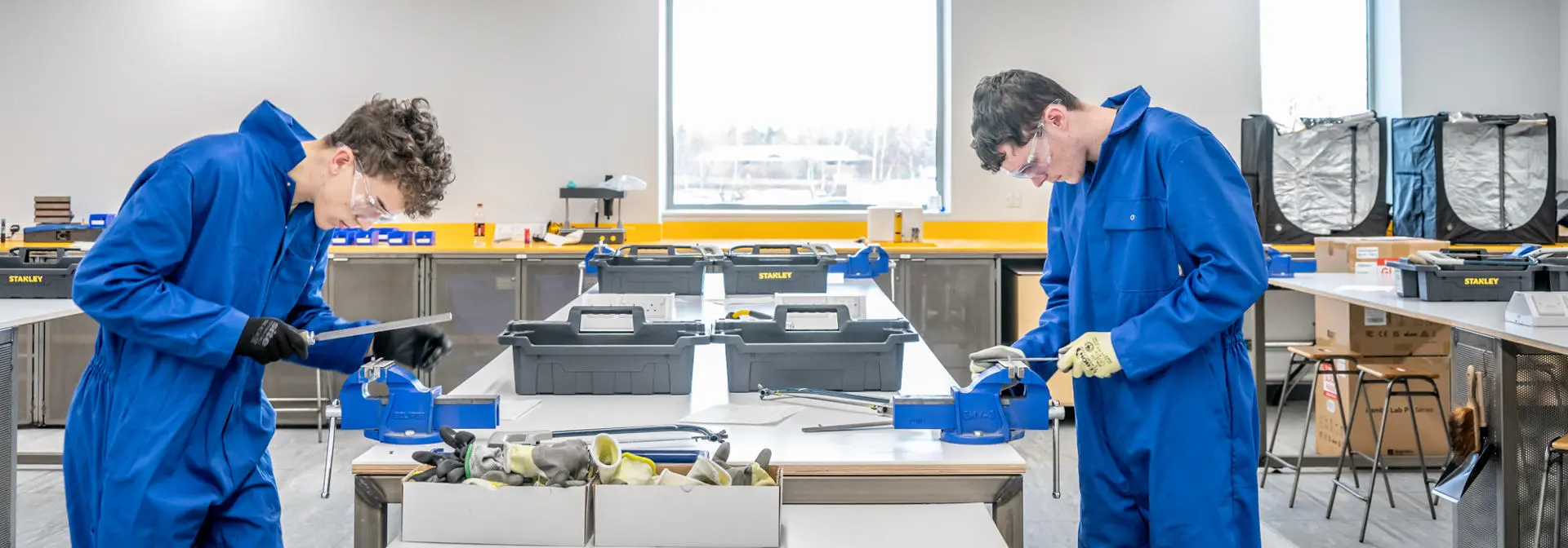 Two students working in a maker lab with PPE on